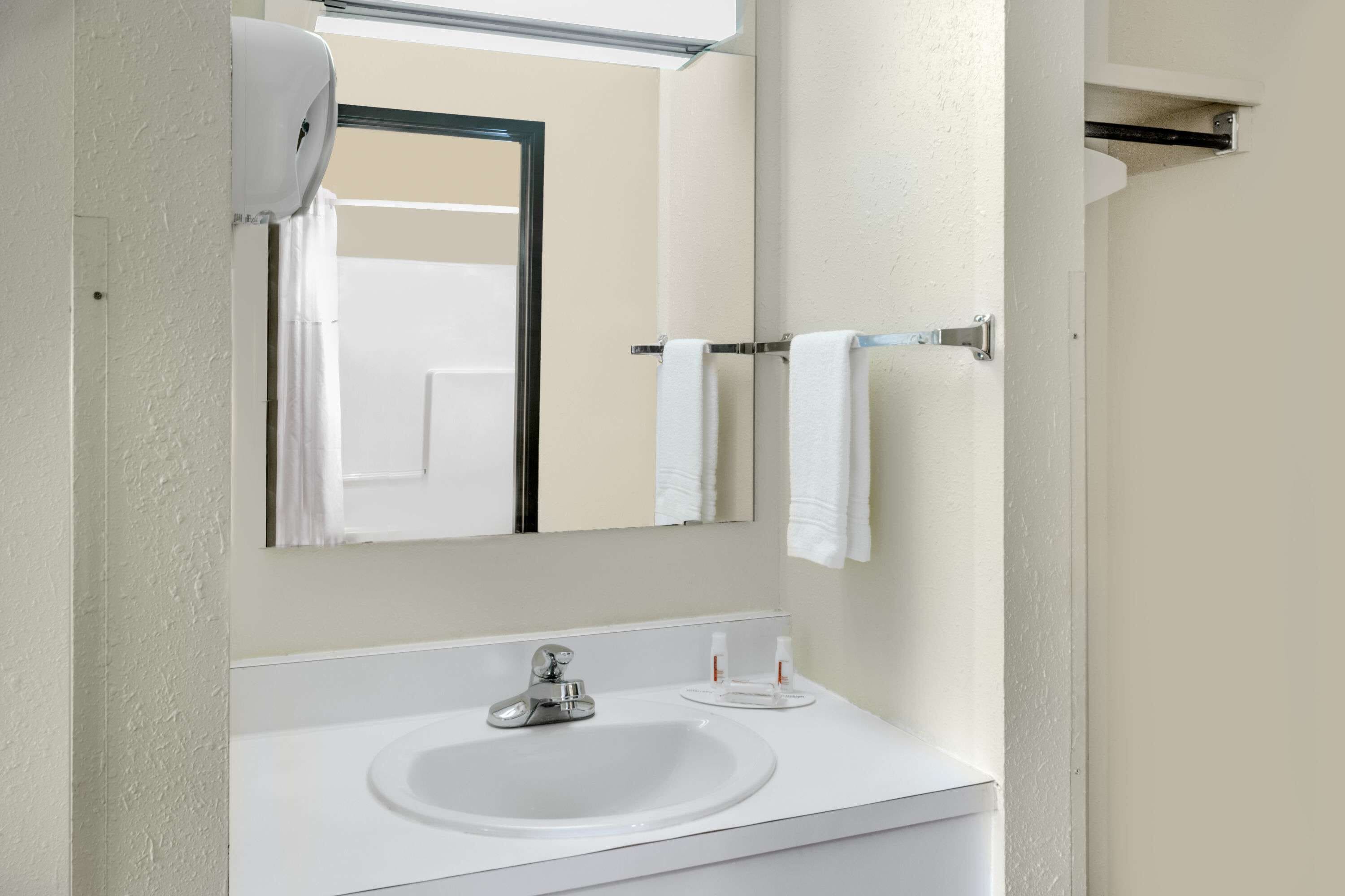 A bathroom with a white sink, a mirror, and a towel rack.