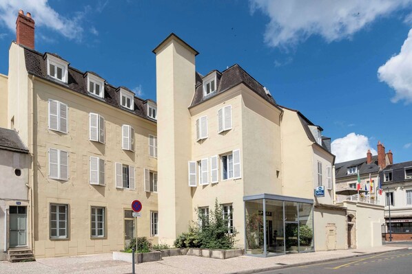 A multi-story building with a beige facade, white shutters, and a clear blue sky. - Best Western De Diane (Nevers)