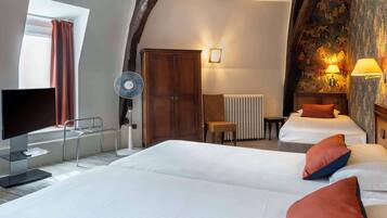 A hotel room with two beds, a TV, a fan, and a large window with curtains.