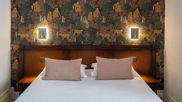 Una habitación de hotel con una cama grande, dos mesitas de noche y una pared decorada con un tapiz detallado.