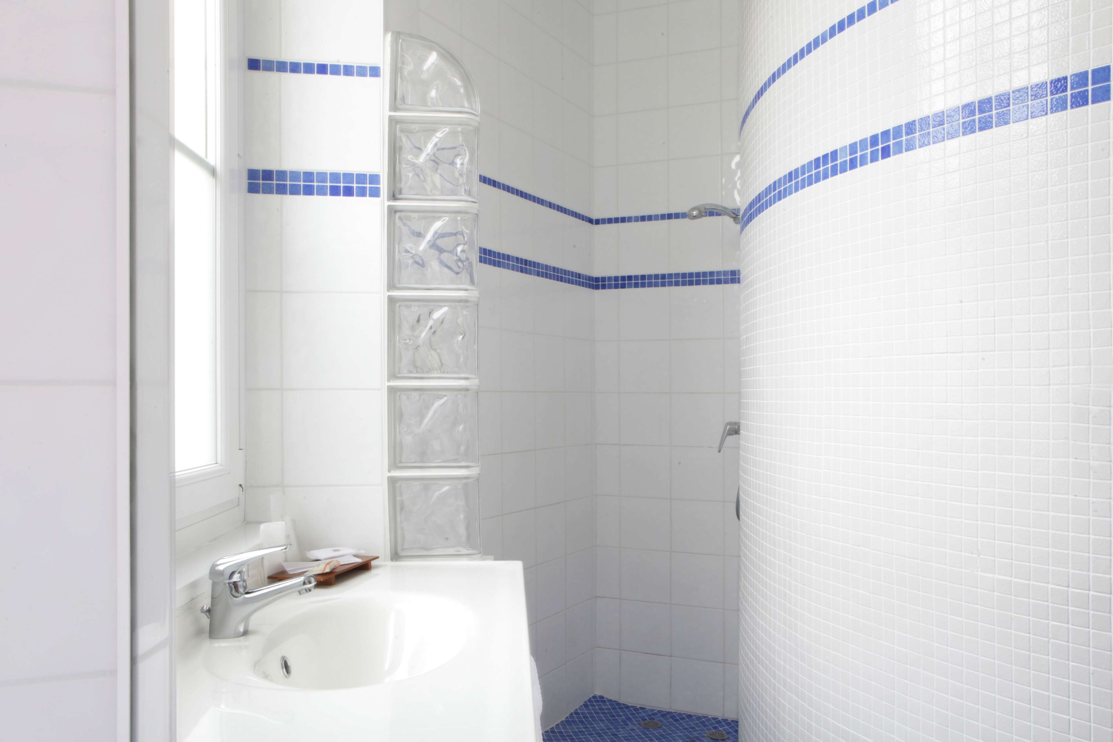A bathroom with a white sink, a mirror, and a shower area.