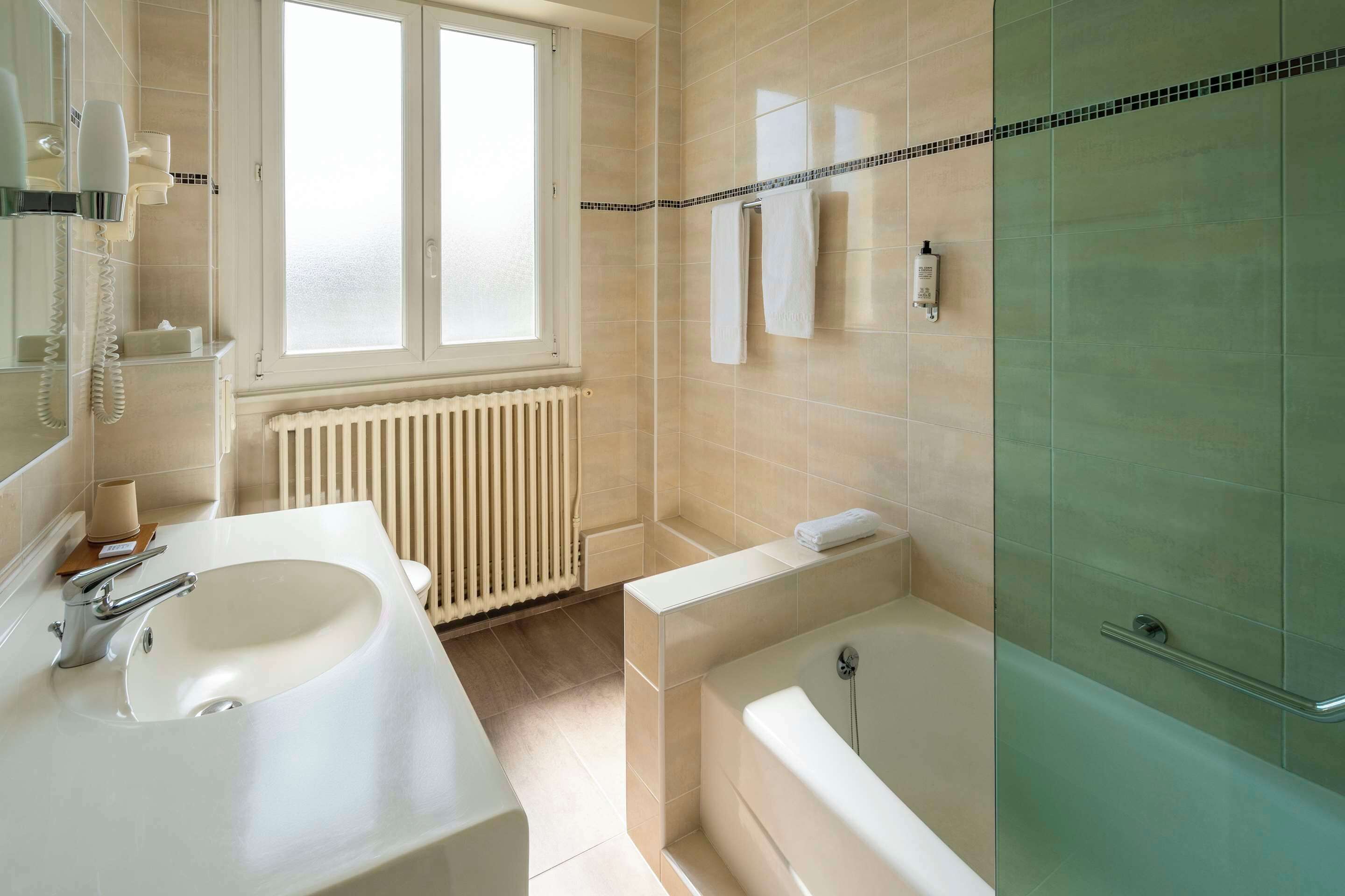 A modern bathroom with a large sink, a bathtub, and a glass shower enclosure.