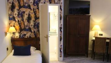 A hotel room with a bed, a wardrobe, a television, and a desk with a chair.
