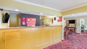 A reception area with a counter, a clock, and a dining area with chairs and a table.