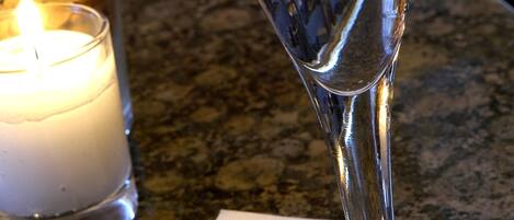 A martini glass with olives on a marble countertop, a lit candle, and a napkin with "OLIVE'S" text.