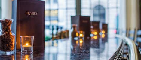 Una zona de bar con una caja de color oscuro con el rótulo "OLIVER'S" y una vela encendida en un candelabro.