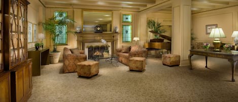 A spacious living room with a fireplace, comfortable seating, and a piano.