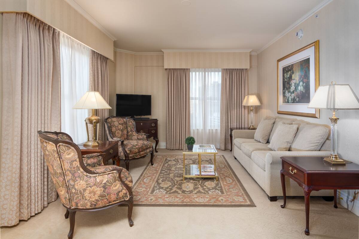A living room with a sofa, two armchairs, a coffee table, a television, and a painting on the wall.