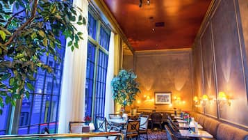 Un hall d’hôtel doté d’une grande fenêtre, d’un espace salon et d’une plante en pot.
