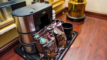 Una cafetera con un paquete de Starbucks y una taza sobre una bandeja.
