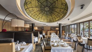 A restaurant with a high ceiling and a mosaic dome, featuring tables set for dining with chairs and a bar area. - Beechwood Hotel (Worcester)
