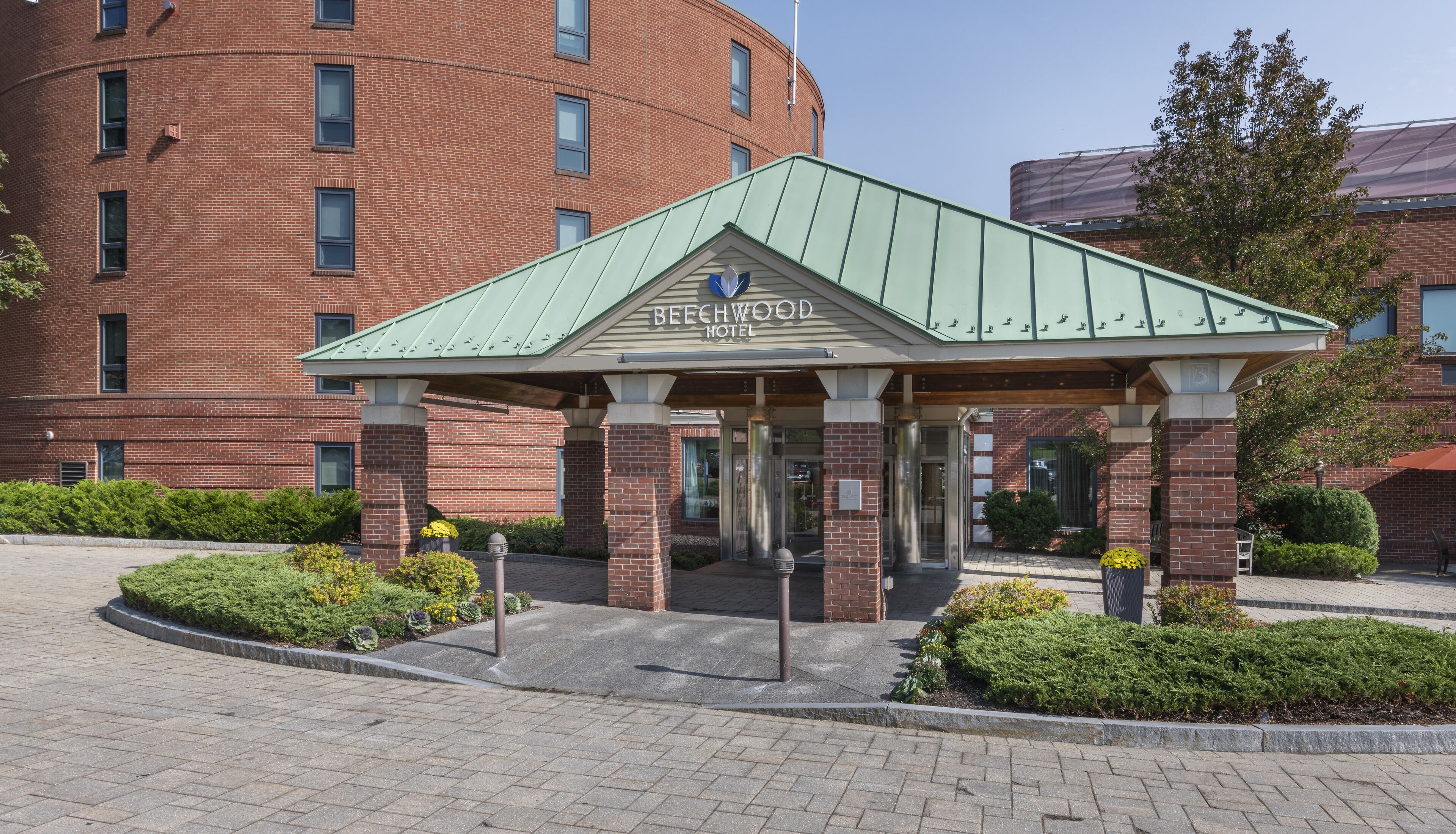 A hotel entrance with a green roof, brick facade, and a sign reading "Beechwood Hotel".