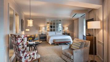 A hotel room with a bed, a desk with a chair, a sofa, and a lamp.