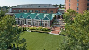 A large building with a green roof, multiple windows, and a courtyard with outdoor seating. - Beechwood Hotel (Worcester)