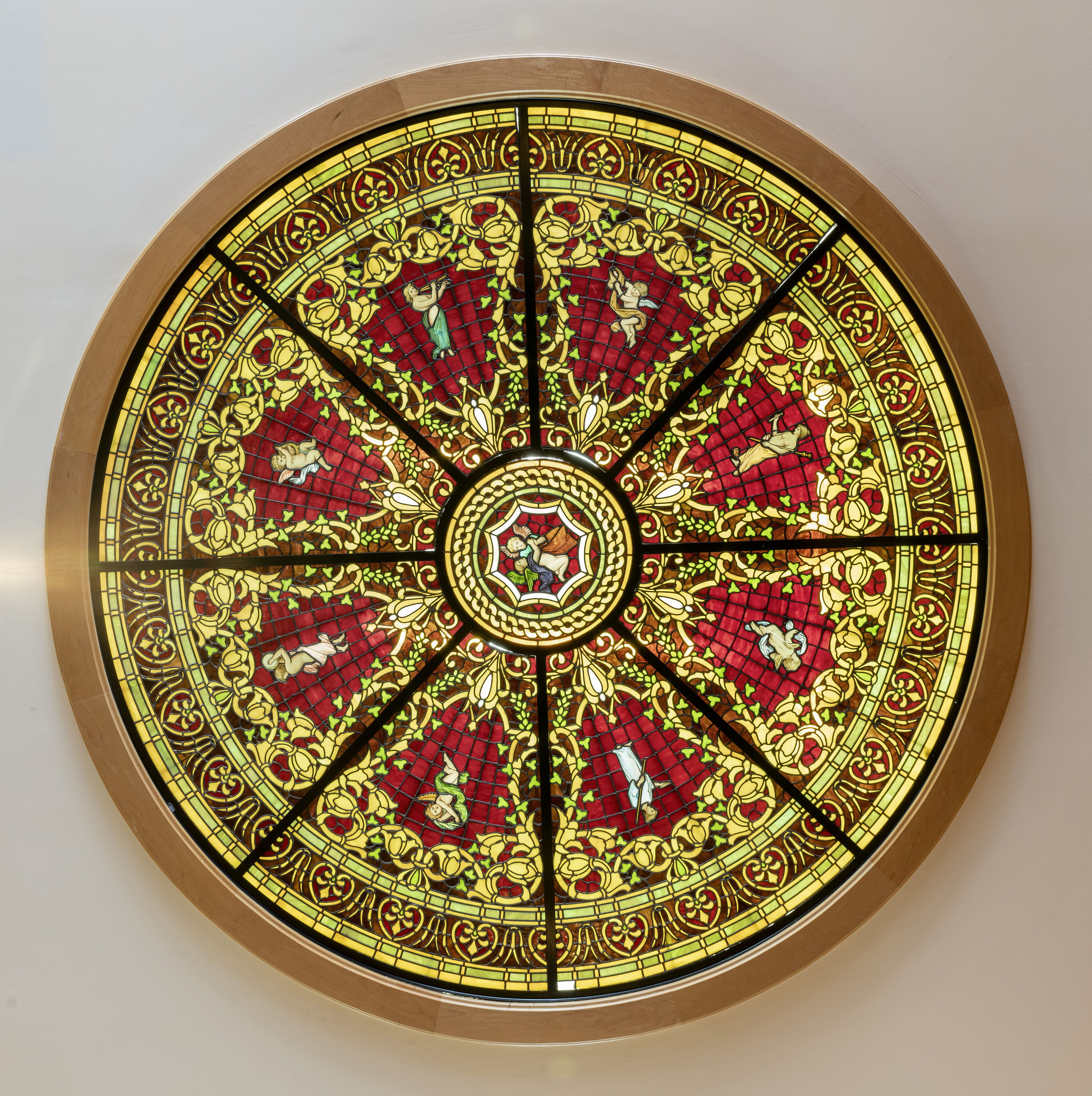 A circular stained glass window with intricate designs and a central emblem.