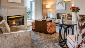 A well-lit living room with a fireplace, a sofa, a coffee table, and a patterned rug. - Beechwood Hotel (Worcester)
