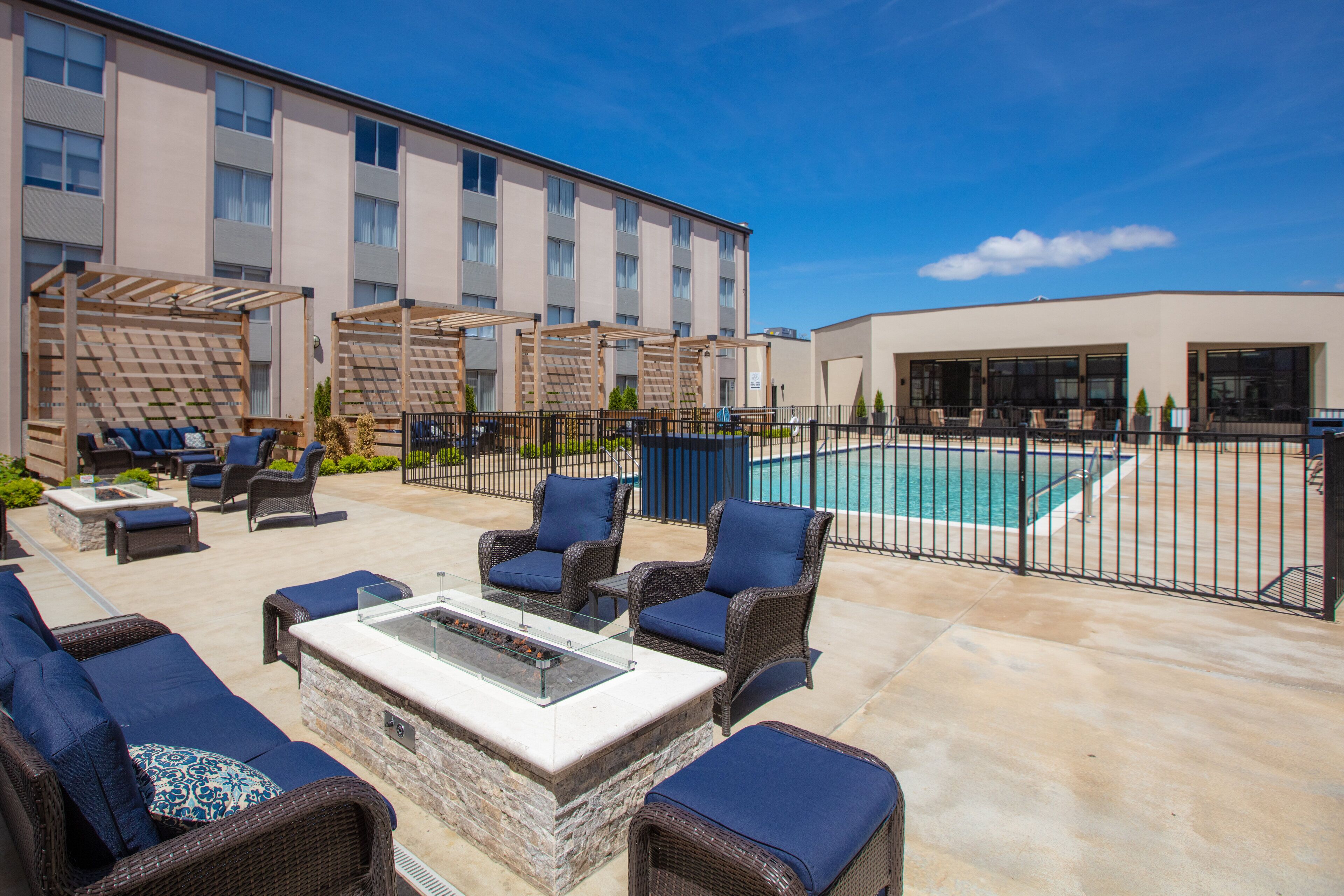 A rooftop patio with outdoor furniture, a pool, and a building with multiple windows.