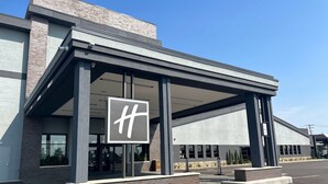 Ein modernes Hotel mit einem auffälligen 'H'-Logo, einer überdachten Eingangshalle und einer Ziegel-Fassade.