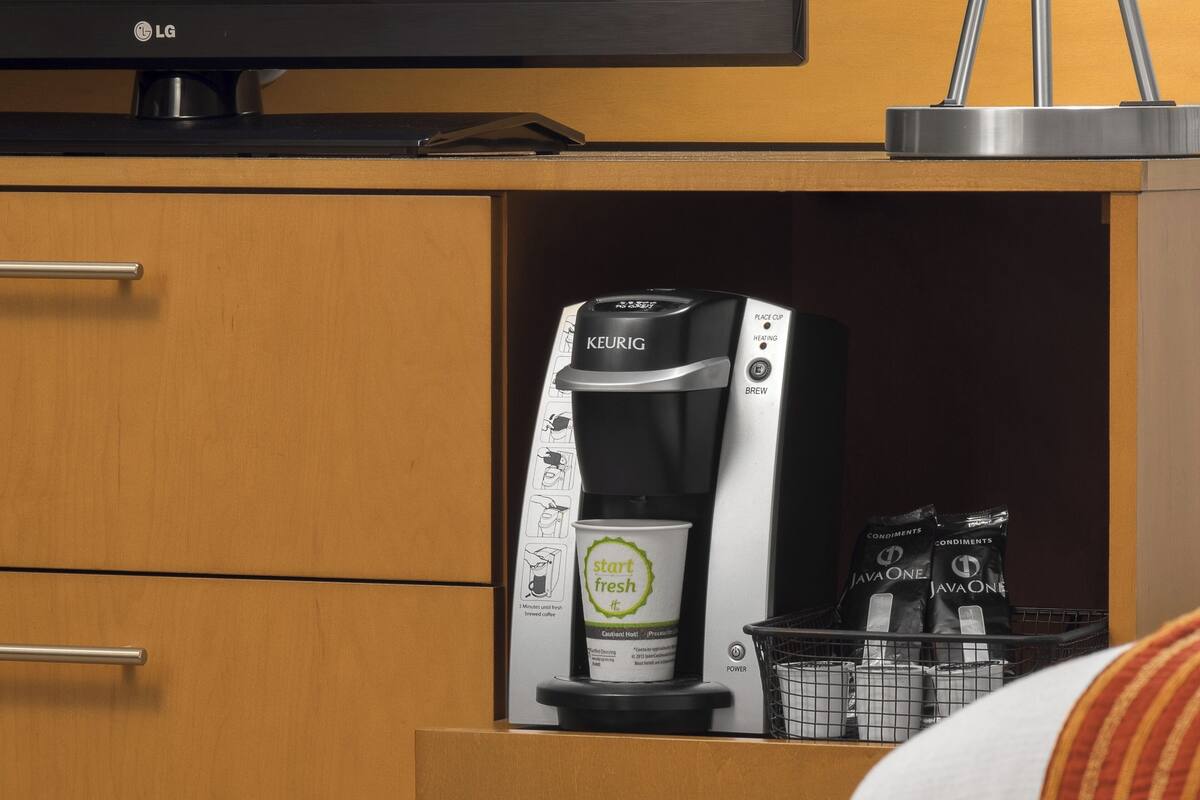 Gessador de cafè amb una capsula de cafè i una tassa de cafè damunt un taulell.