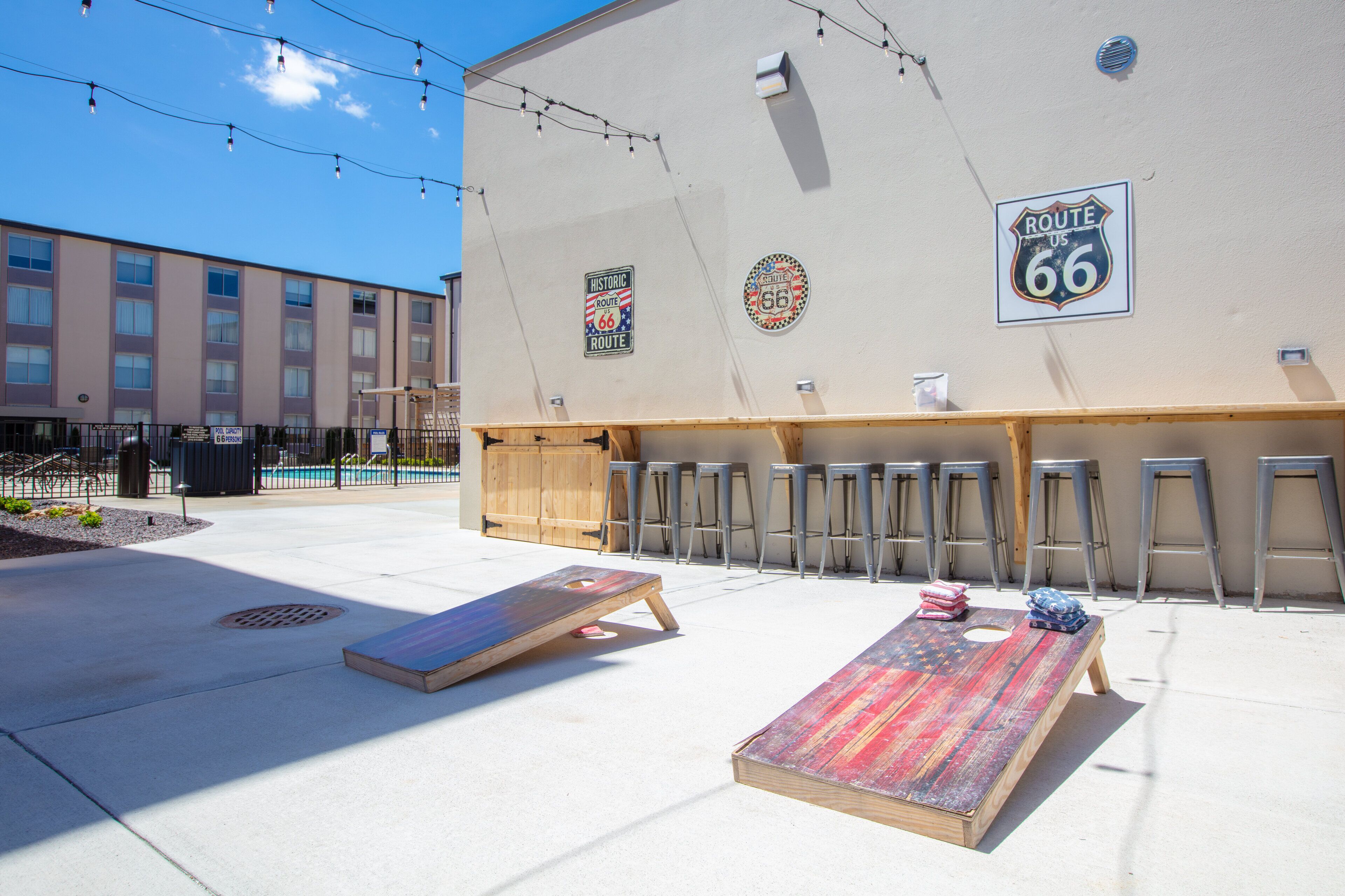 An outdoor seating area with a pool, bar stools, and a mural of Route 66.