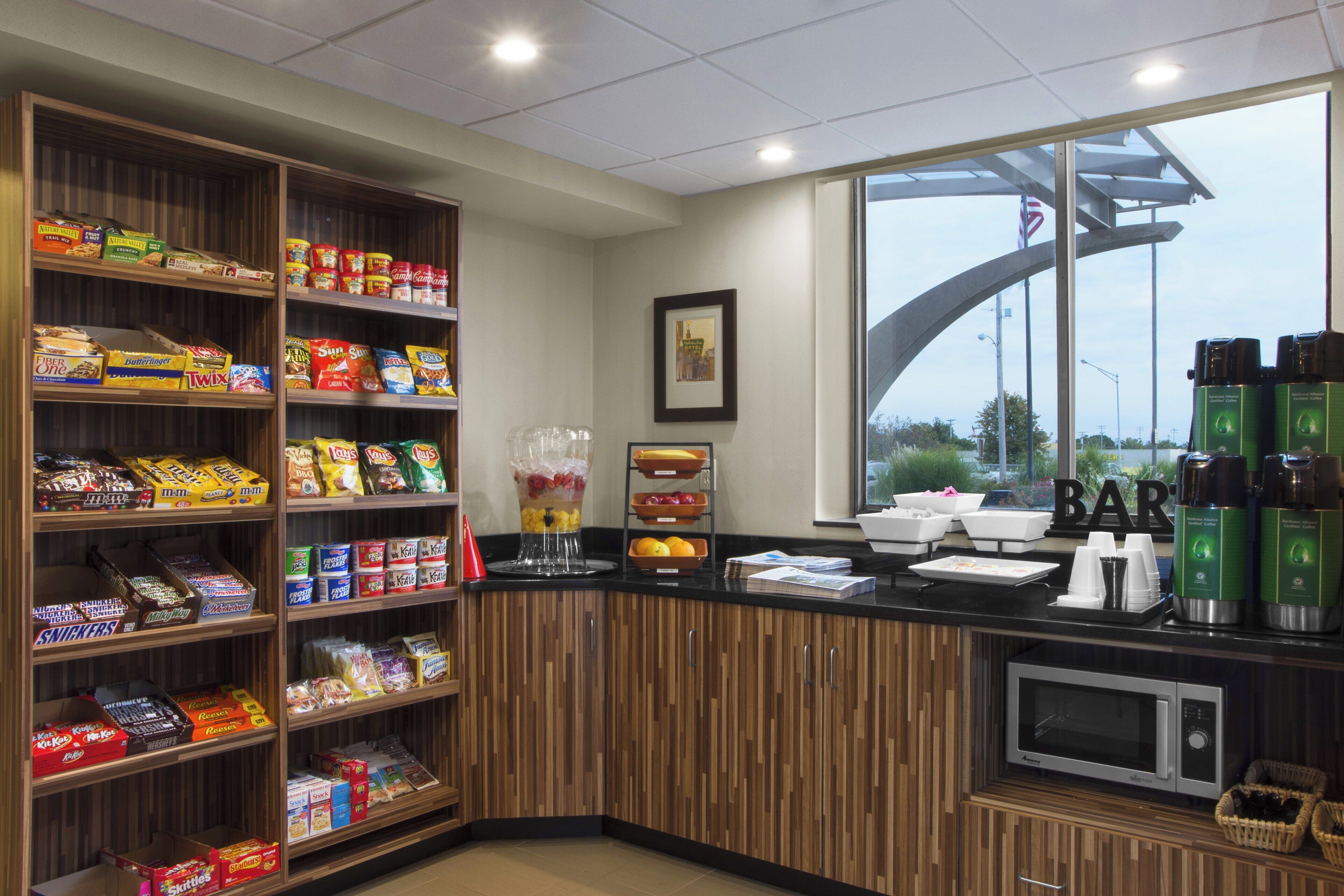 A snack bar with shelves stocked with various snacks and a coffee station with branded dispensers.