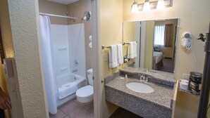 A bathroom with a bathtub, toilet, sink, and a large mirror.