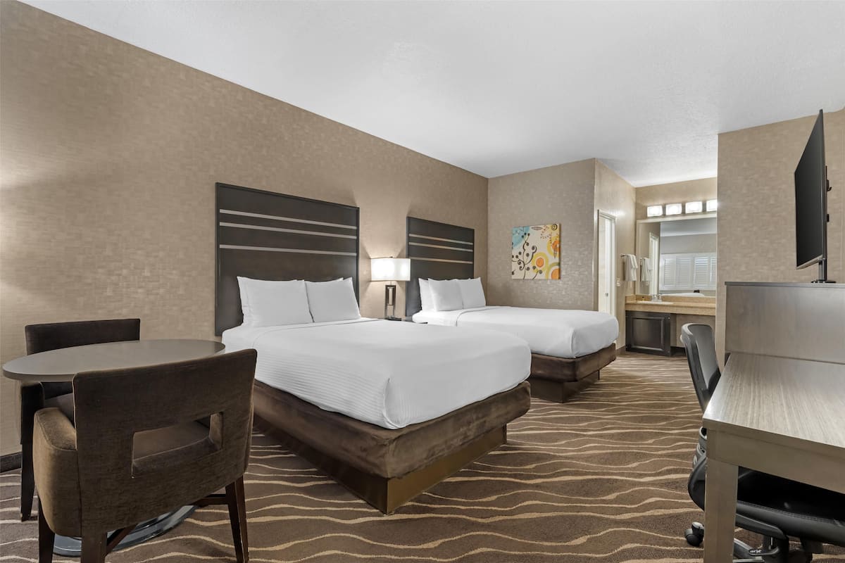 Ein Hotelzimmer mit zwei Betten, einem Schreibtisch, einem Stuhl und einem Fernseher.