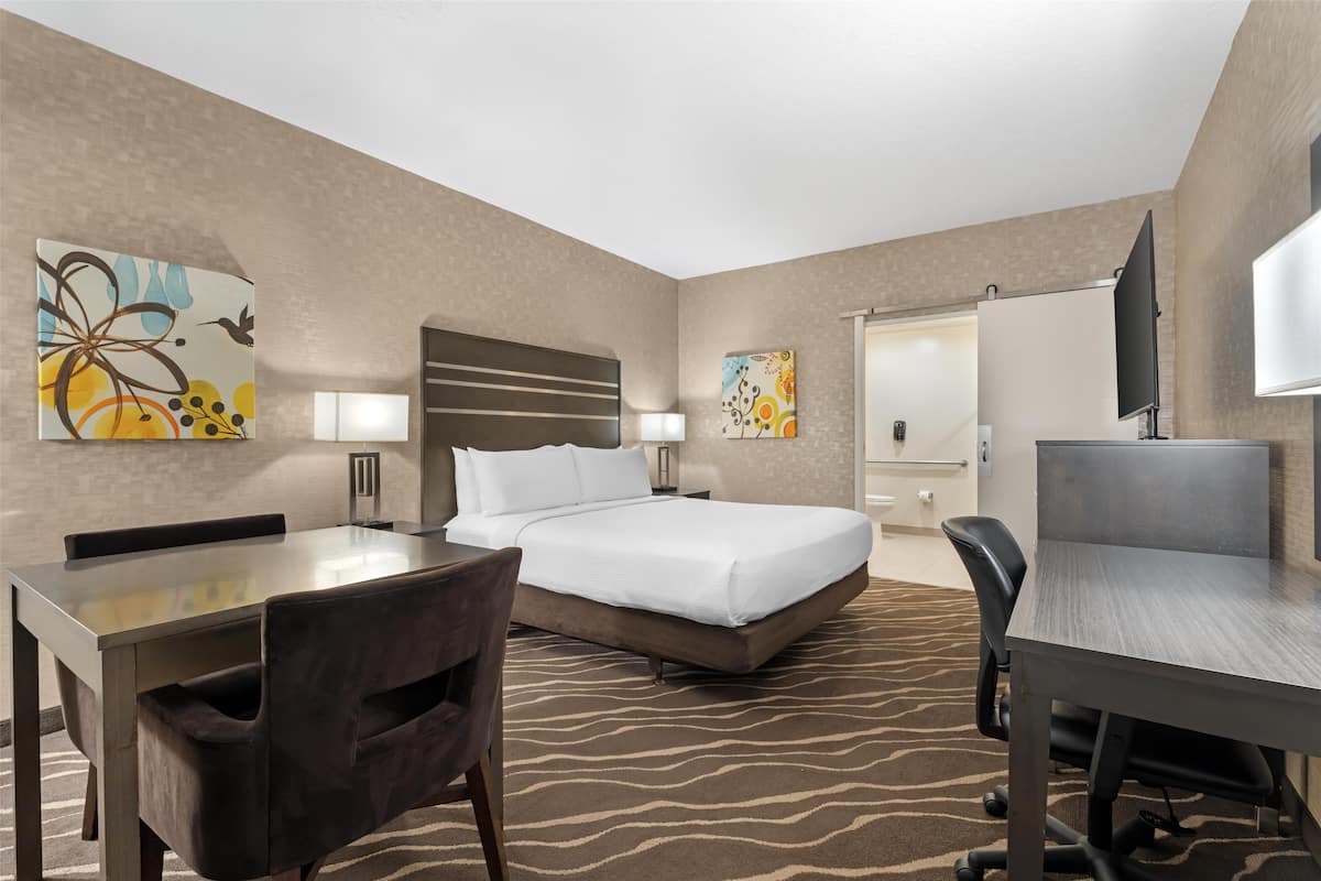 Ein Hotelzimmer mit Bett, Schreibtisch, Stuhl, Fernseher und Bildern an den Wänden.