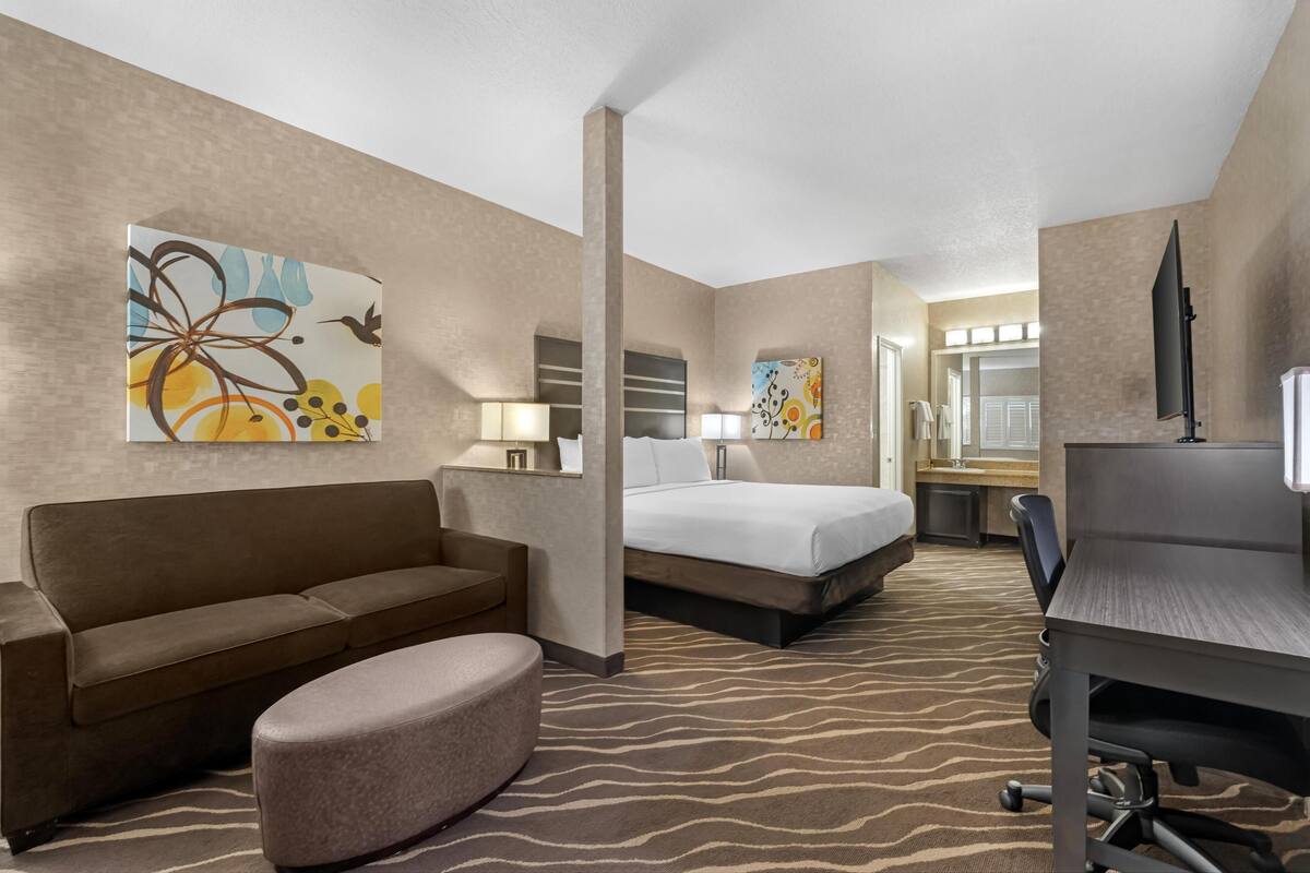 Ein Hotelzimmer mit Bett, Schreibtisch, Sofa und Sessel.