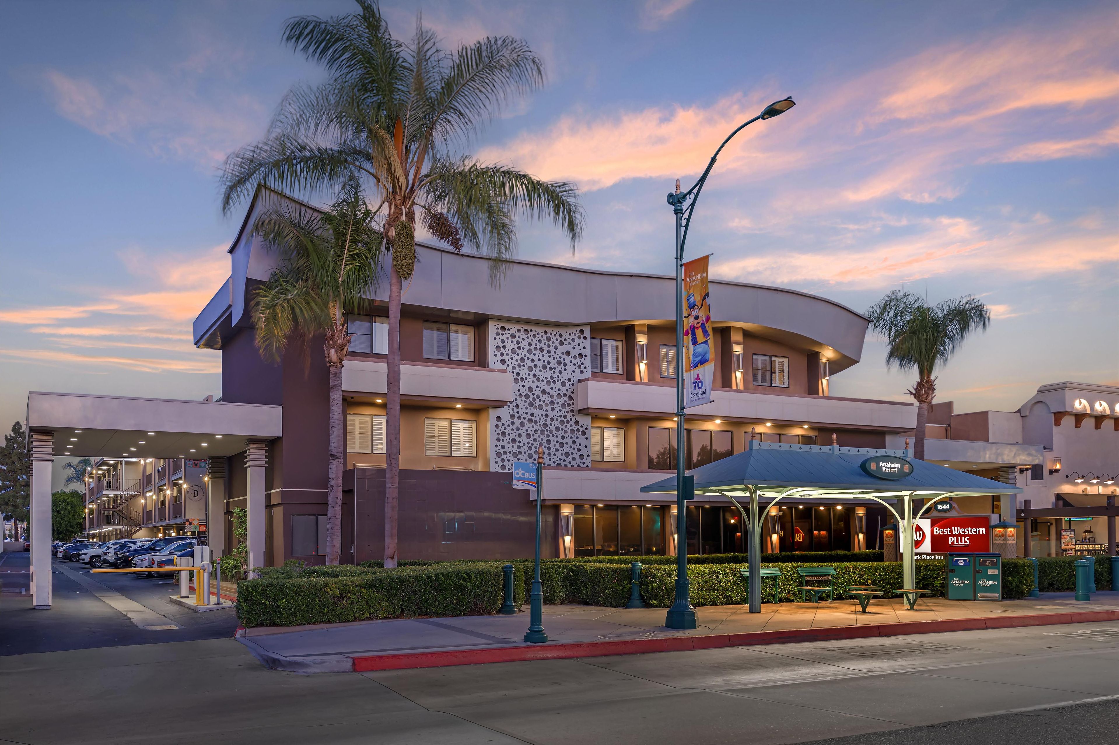 A hotel with a covered outdoor seating area, a palm tree, and a Best Western Plus sign.