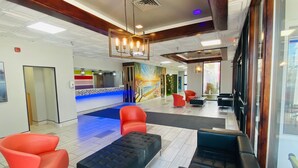 A modern lobby with a reception desk, seating area, and a view through large windows. - Rest and Relax Inn (Pensacola)