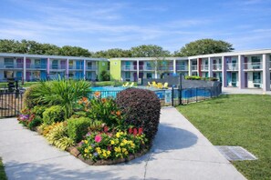 A motel with a swimming pool, surrounded by a garden with various plants and flowers. - Rest and Relax Inn (Pensacola)