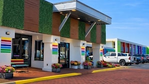 A building with a modern design, featuring a green and brown facade, multiple doors, and a brick-paved entrance area. - Rest and Relax Inn (Pensacola)