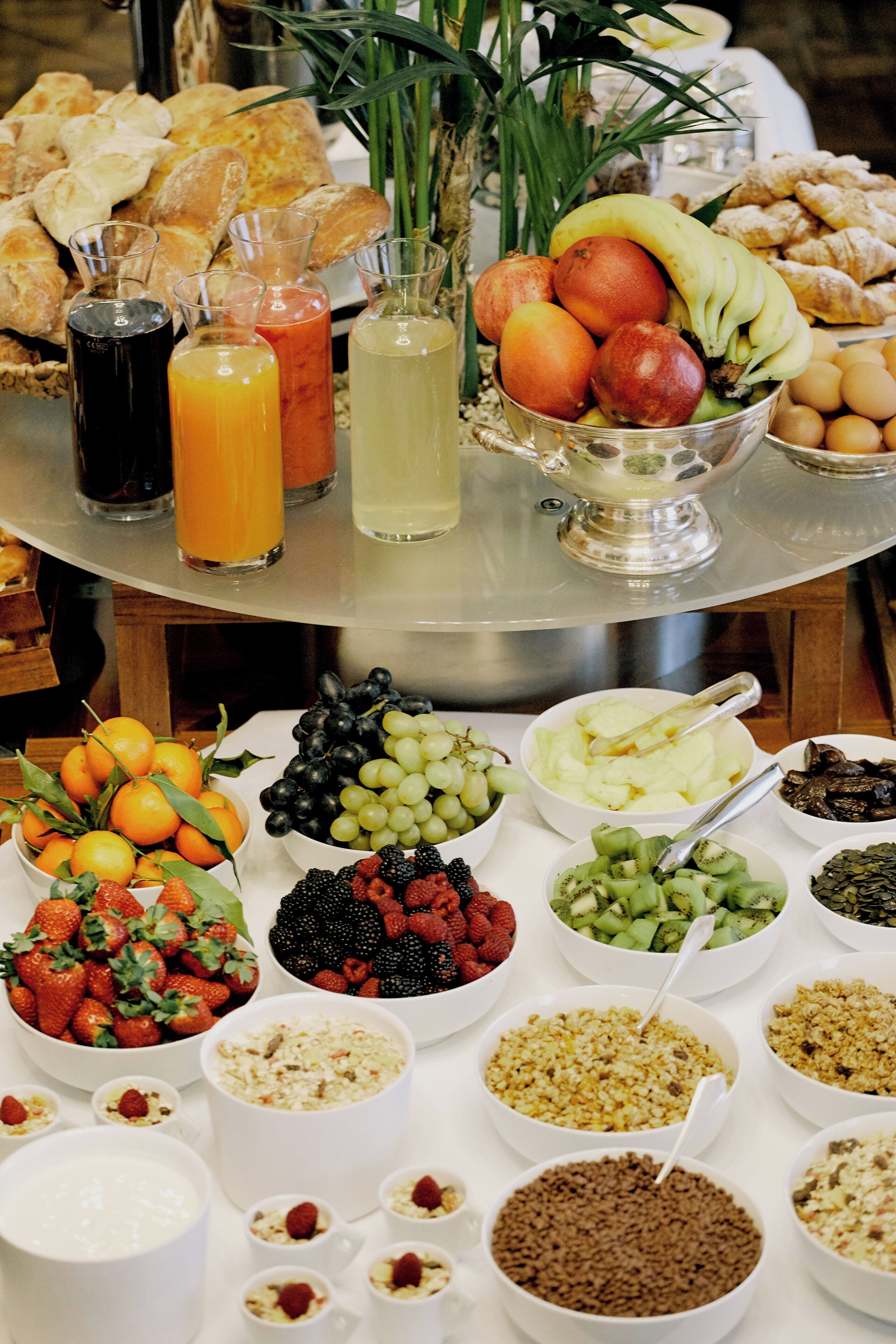 A breakfast buffet with various fruits, pastries, and beverages.