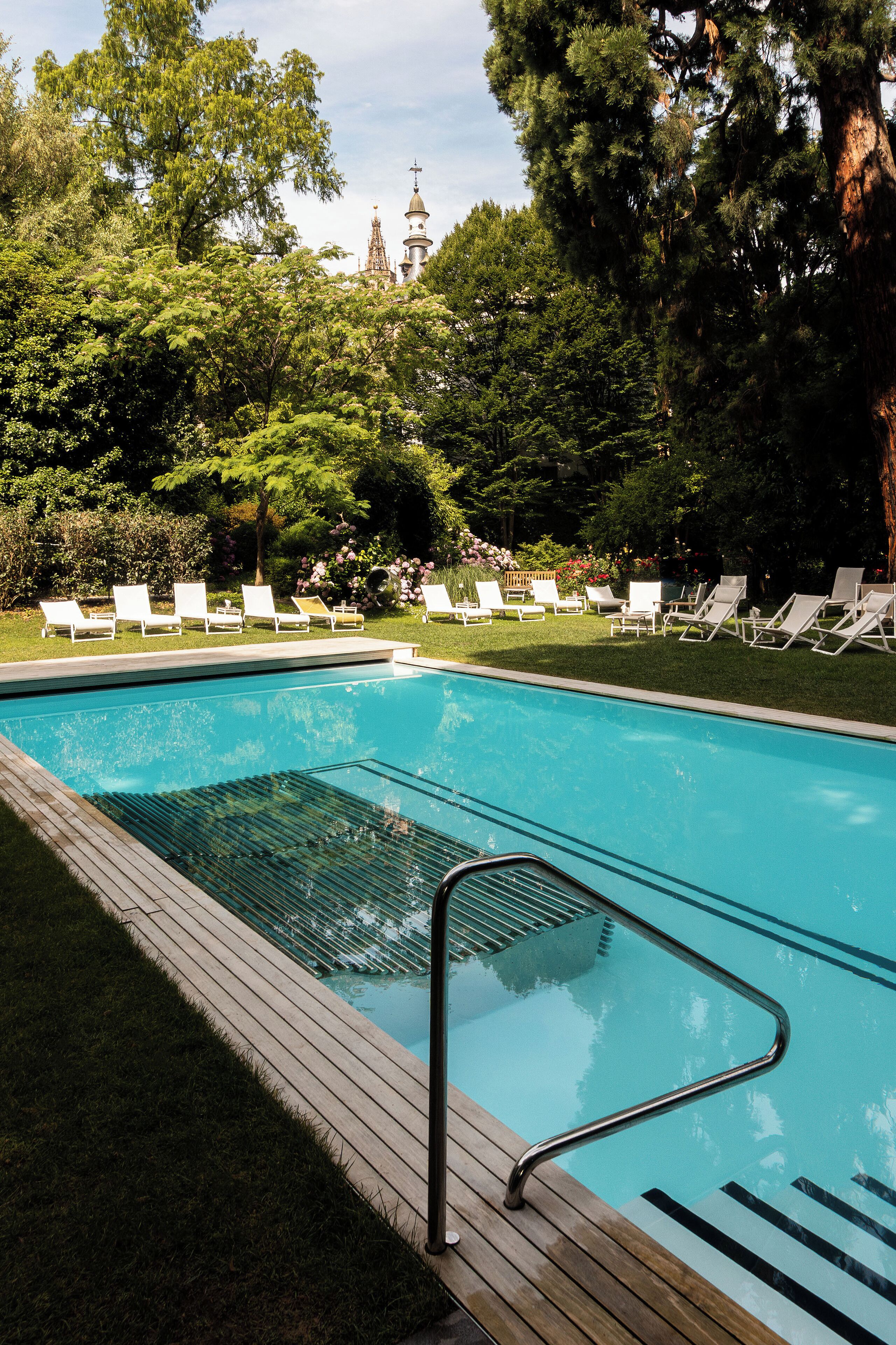 A swimming pool with a wooden deck and lounge chairs.