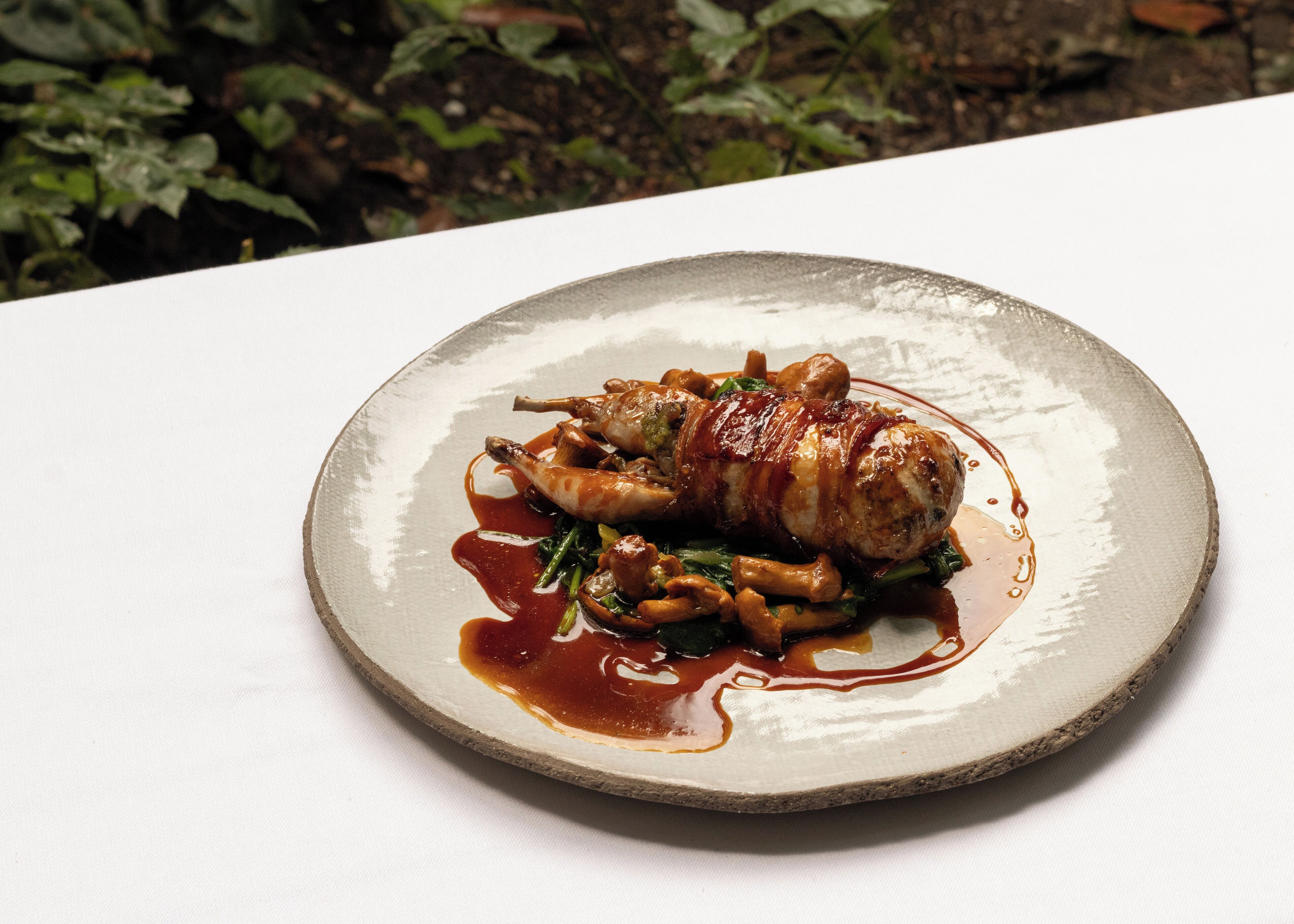 A plate of food with a meat dish, vegetables, and sauce on a white table.