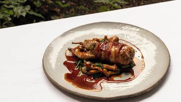 A plate of food with a meat dish, vegetables, and sauce on a white table.