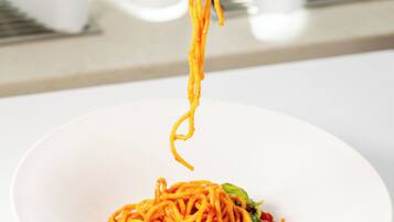 A person holding a fork with spaghetti over a white plate.