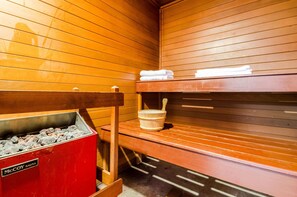 Relax in a serene sauna room with a traditional charcoal heater and comfortable seating.