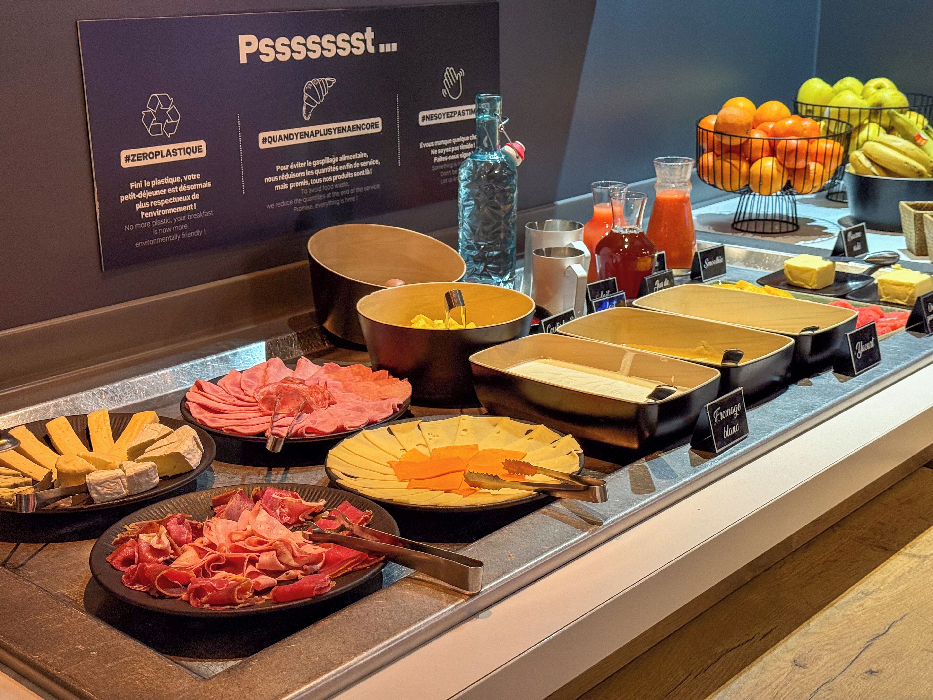 Un bufé con diversas opciones de comida y un cartel que promueve el uso cero de plástico.
