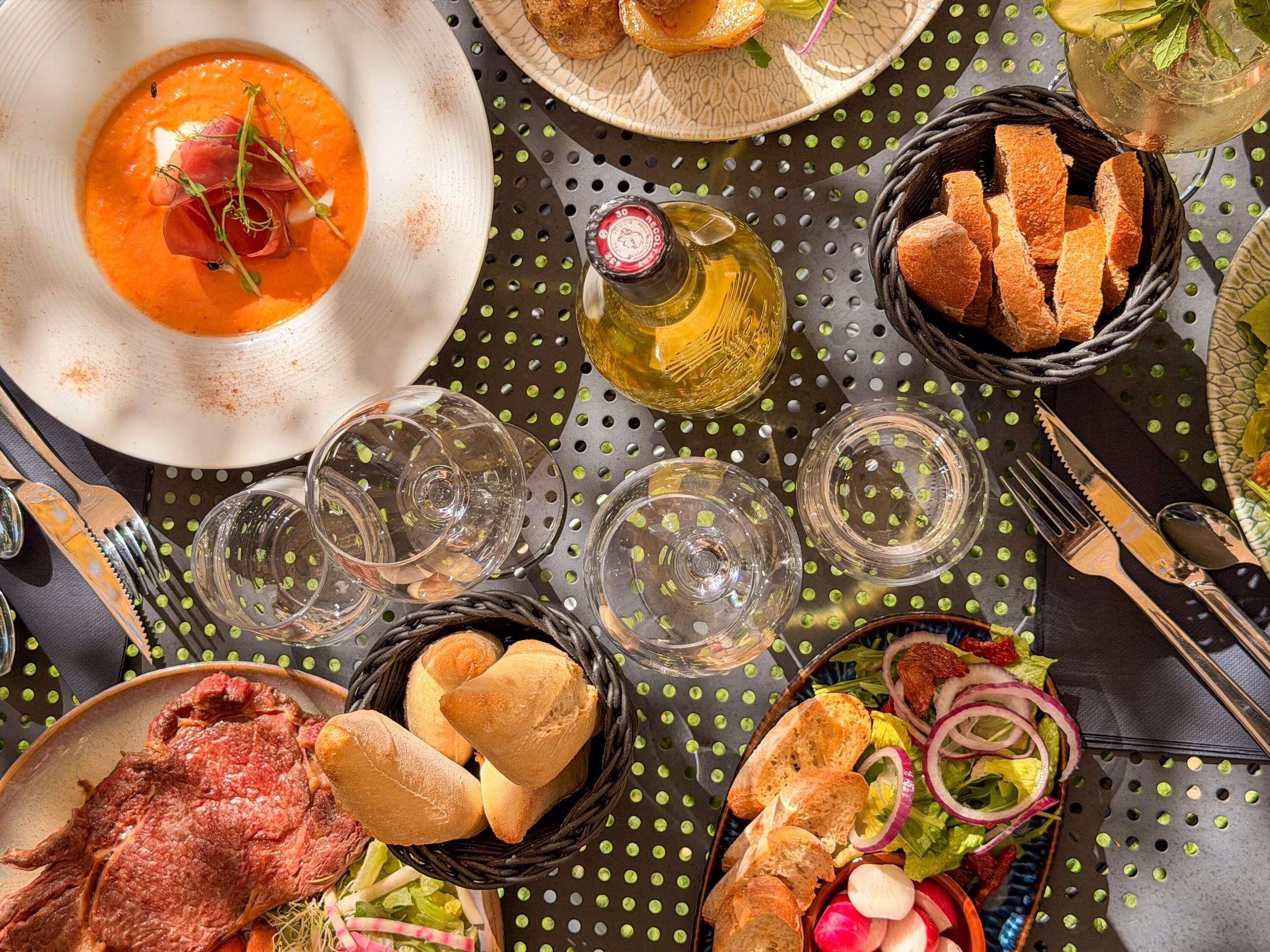 A dining table with various dishes, including soup, bread, and a bottle of olive oil.