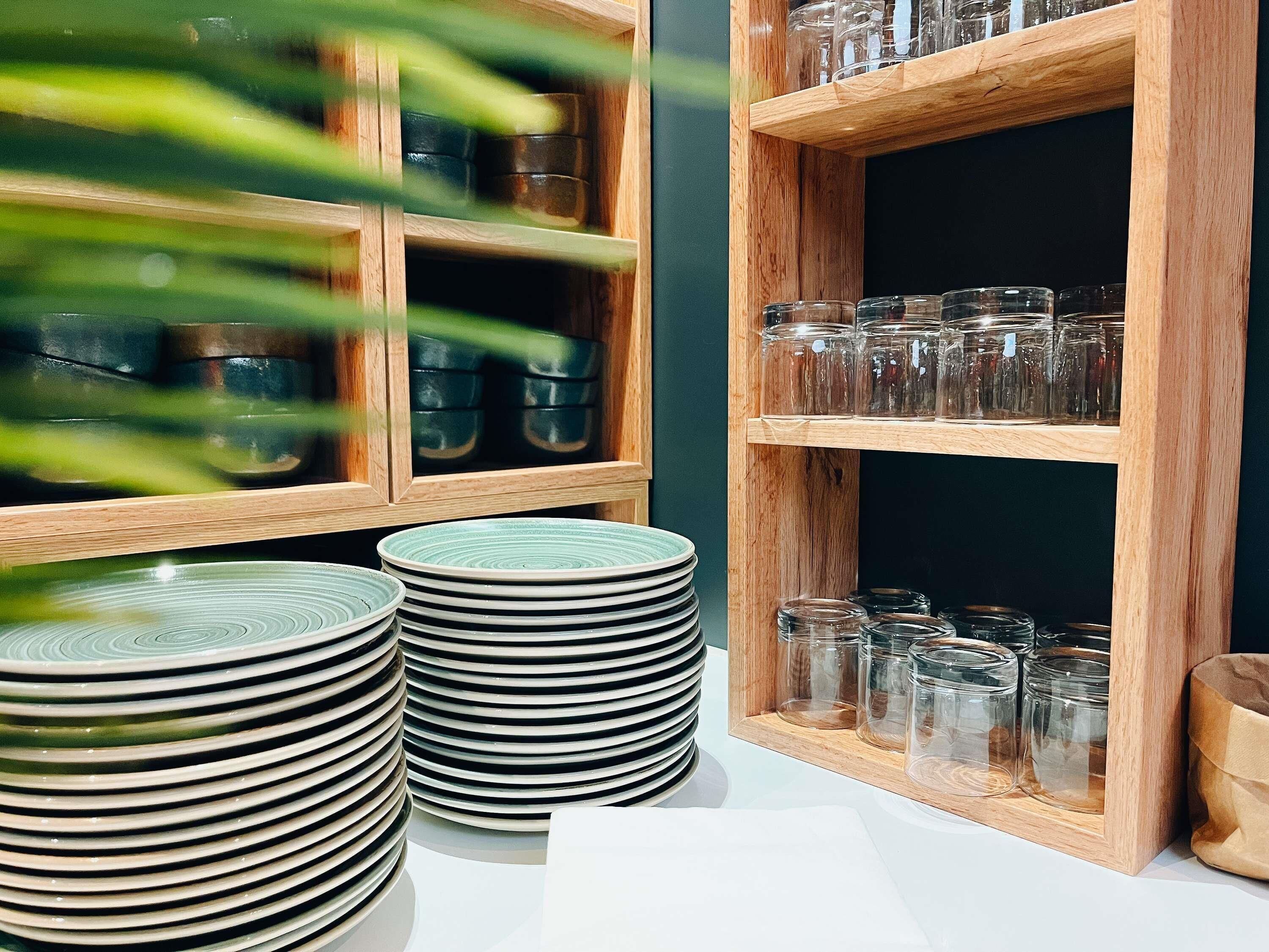 A kitchen area with wooden shelves holding glass jars and plates.