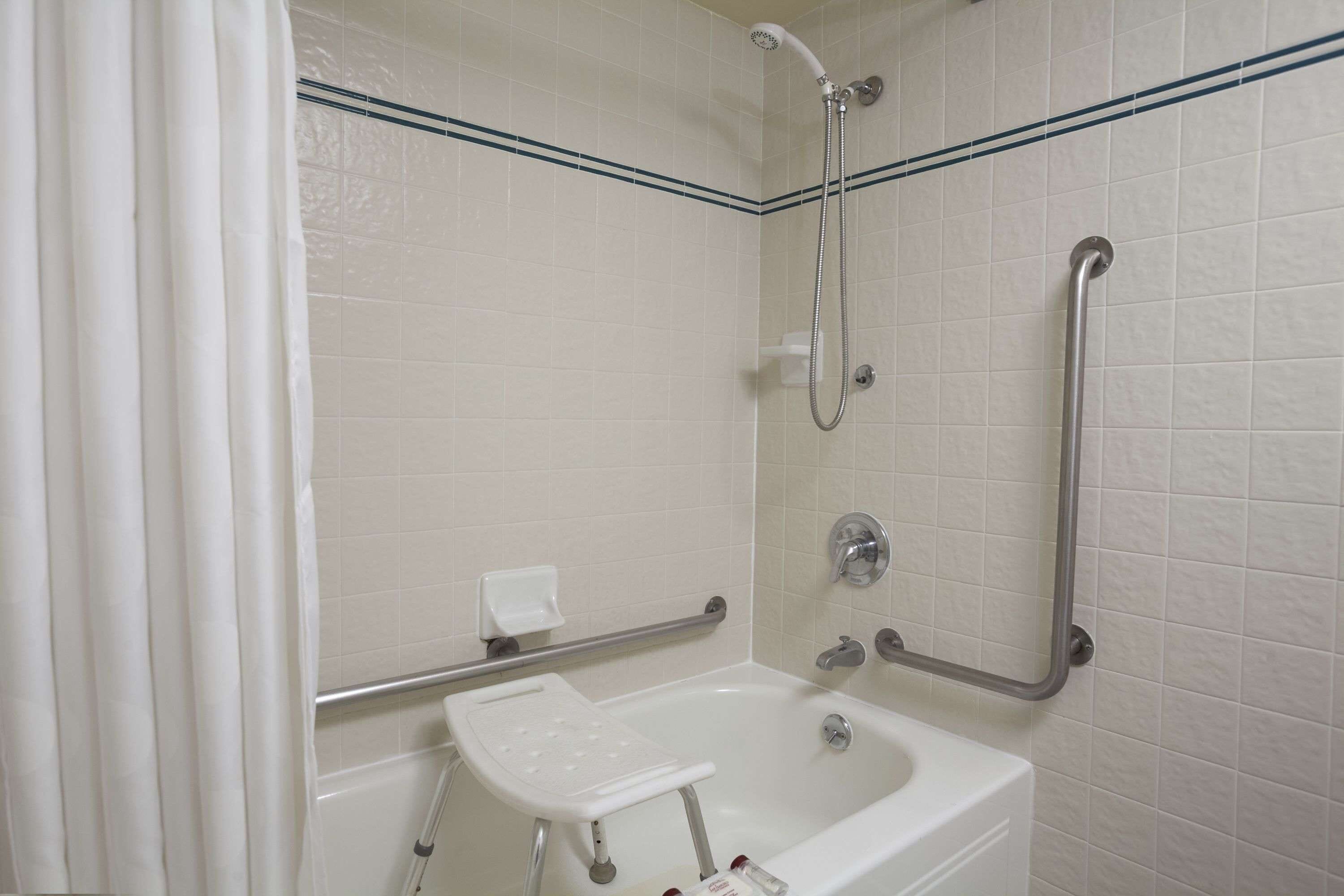 Un baño con bañera, ducha y barra de apoyo.