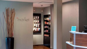 A reception area with a modern design, featuring a reception desk, a wall-mounted display, and a shelving unit with various items. - Courtyard by Marriott Mt. Laurel (Mount Laurel)