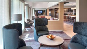 A modern hotel lobby with seating areas, a reception desk, and a visible kitchen area. - Courtyard by Marriott Mt. Laurel (Mount Laurel)