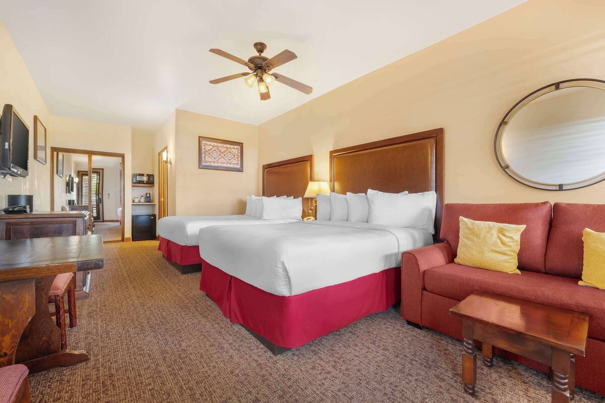 Una habitación de hotel con una cama grande, un sofá, un escritorio y un ventilador de techo.