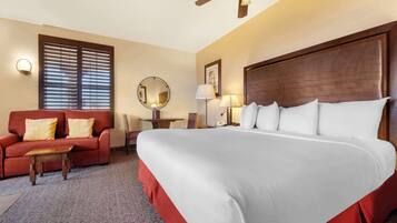 Une chambre d’hôtel avec un grand lit, un canapé rouge, une petite table et un ventilateur de plafond.