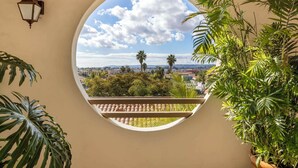 Una ventana redonda con vista a un paisaje urbano, palmeras y un cielo despejado.