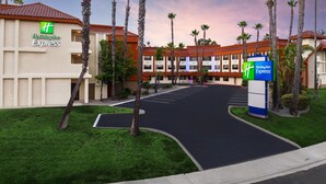 Un hôtel Holiday Inn Express doté d’un parking et de palmiers.