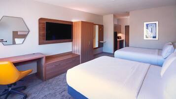 A hotel room with a bed, a desk, a chair, a wardrobe, and a television mounted on the wall.